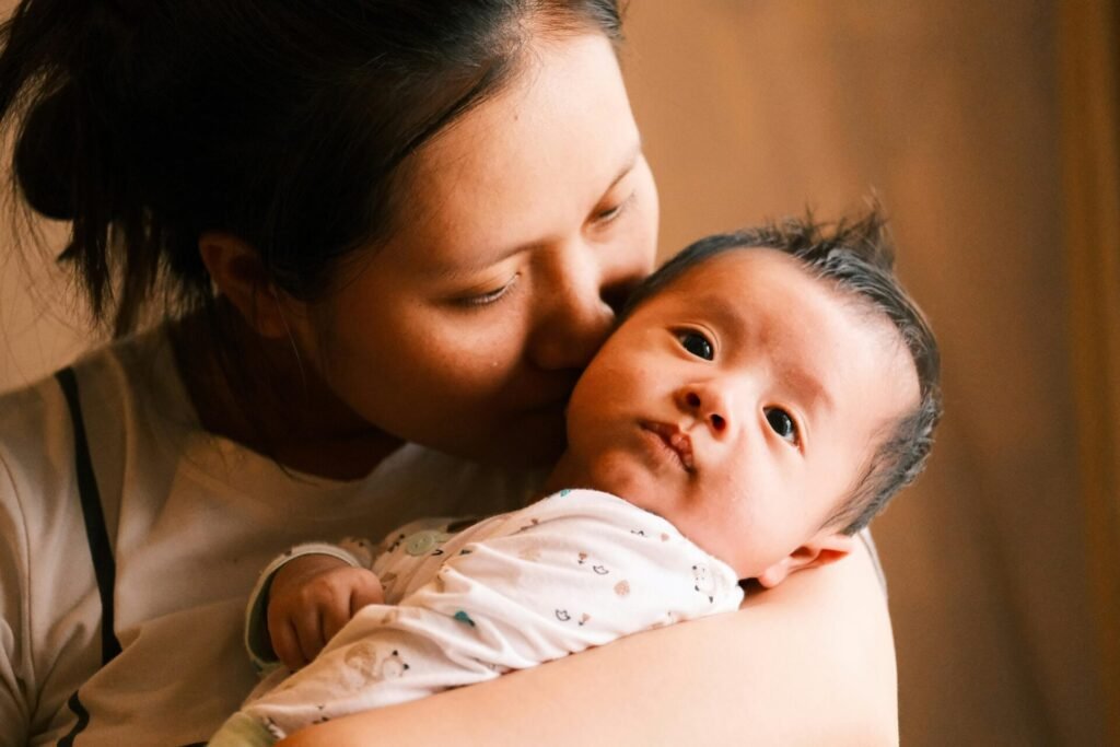 Woman kissing baby, baby looking into camera